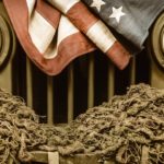 A close of a retro military Jeep grille is shown with a rope and an American flag on it.