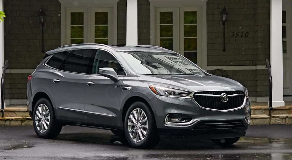 A grey 2020 Buick Enclave, which is a popular option among the Buick SUVs, is parked in front of a house.