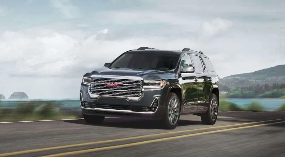 A black 2020 GMC Acadia, which wins when comparing the 2020 GMC Acadia vs 2020 Kia Telluride, is driving past a bay.