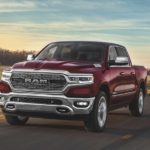 A red 2020 Ram 1500, which wins when comparing the 2020 Ram 1500 vs 2019 Ram 1500, is driving past fields.