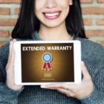 A smiling woman is holding up an iPad that says Extended Warranty on it.