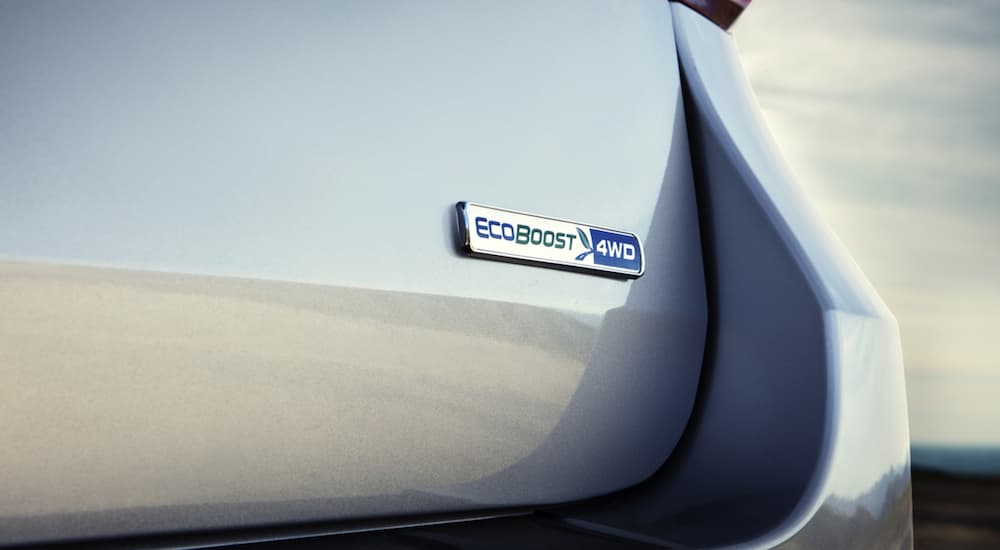 The 2020 Ford Explorer Ecoboost badge is shown in closeup on a silver Explorer.