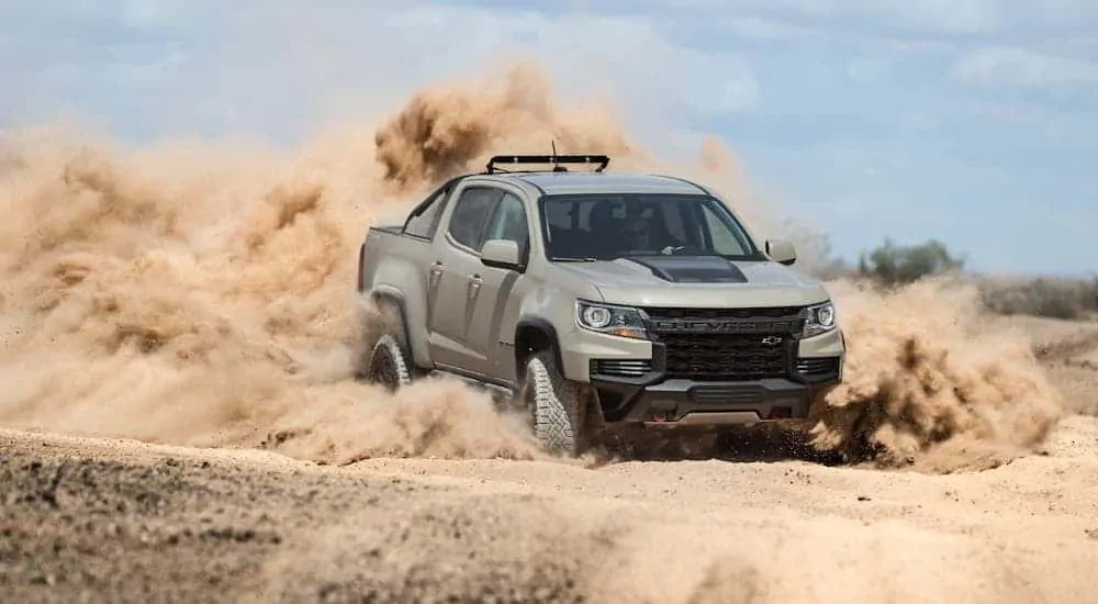 A tan 2021 Chevy Colorado ZR2 is kicking up sand in the desert.