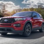 A red 2020 Ford Explorer, which wins when comparing the 2020 Ford Explorer vs 2020 Kia Telluride, is driving on a city street.