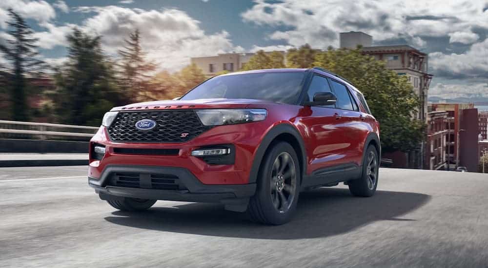 A red 2020 Ford Explorer, which wins when comparing the 2020 Ford Explorer vs 2020 Kia Telluride, is driving on a city street.