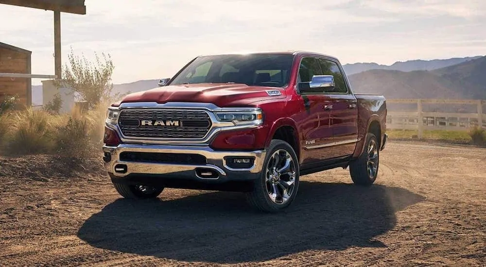 A red 2020 Ram 1500 is parked next to a home next with mountains in the distance.