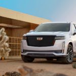 A white 2021 Cadillac Escalade is parked in front of a modern house in a desert area.