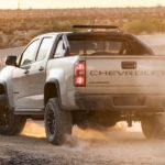 A tan 2021 Chevy Colorado ZR2 is shown from the rear on a dusty dirt road.