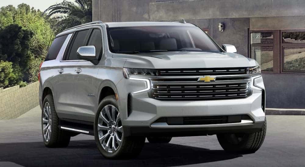A silver 2021 Chevy Suburban is parked in a modern driveway.