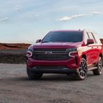 A red 2021 Chevy Tahoe is parked in a parking lot with mountains in the distance.