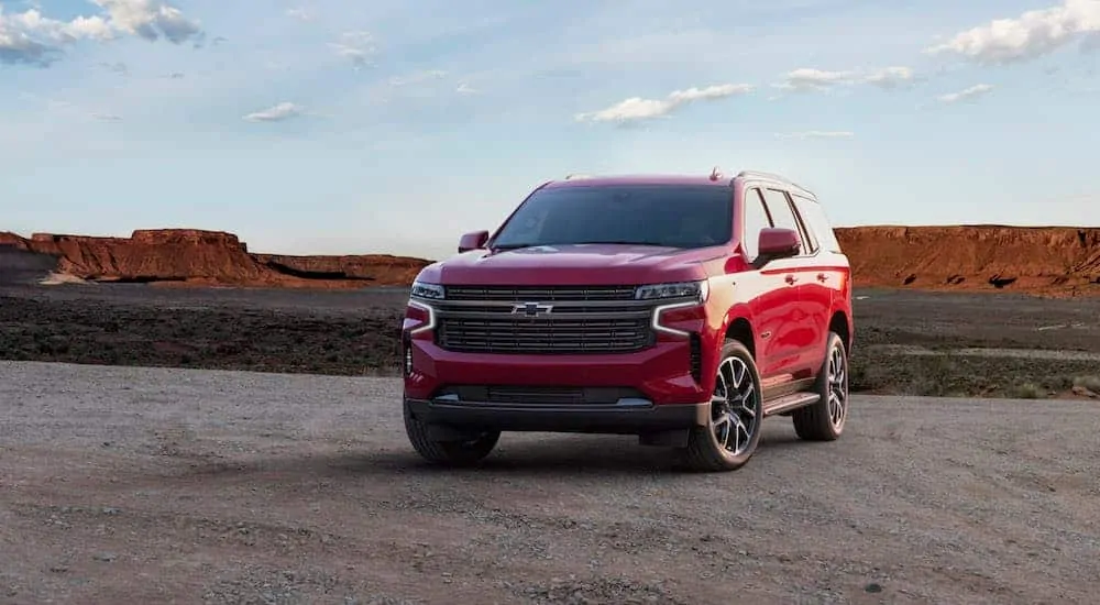 A red 2021 Chevy Tahoe is parked in a parking lot with mountains in the distance.