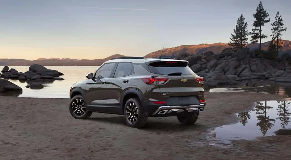 A brown 2021 Chevy Trailblazer is parked on sand while facing a lake at dusk. 