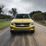 A yellow 2021 Kia Seltos from the front races down a rural road.