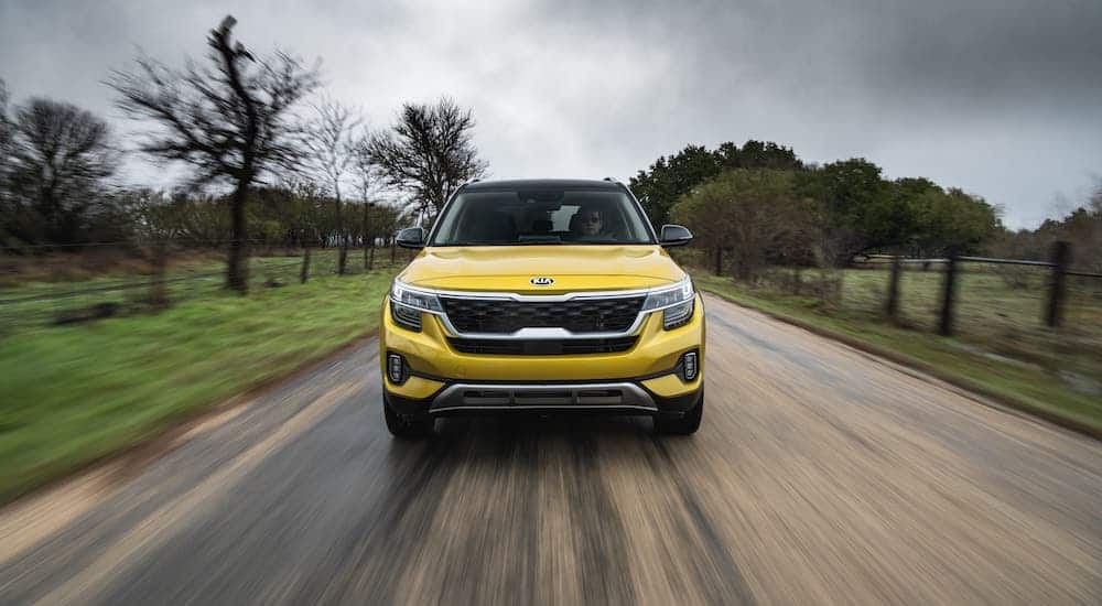 A yellow 2021 Kia Seltos from the front races down a rural road.