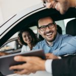 A salesman is talking to a couple as they buy a used car.