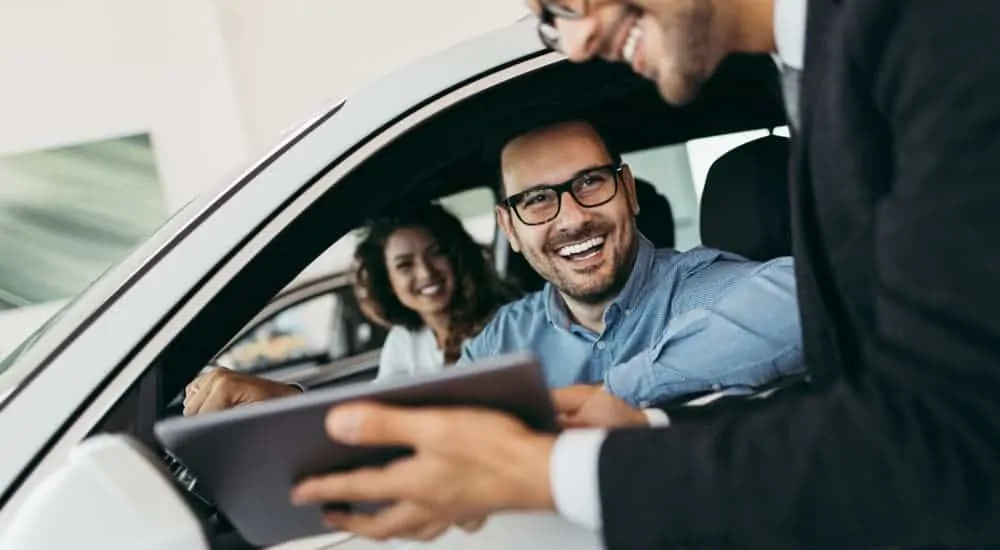 A salesman is talking to a couple as they buy a used car.