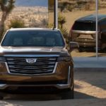 A brown 2021 Cadillac Escalade, which is soon to be a popular option at your local Cadillac dealership, is parked in the desert in front of a mirror.