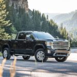 A black 2020 GMC Dealer HD Denali is parked on a woodland highway.