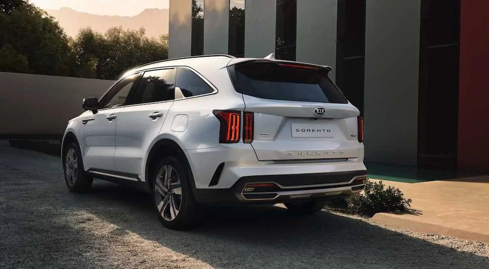 A white 2021 Kia Sorento is parked in a driveway facing away at dusk, see one at a Kia dealer soon.