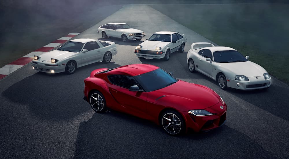 A red 2020 Toyota Supra is surround by white older models after leaving a Toyota dealer near me.