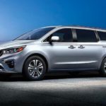 A silver 2020 Kia Sedona is parked in an empty lot at night.