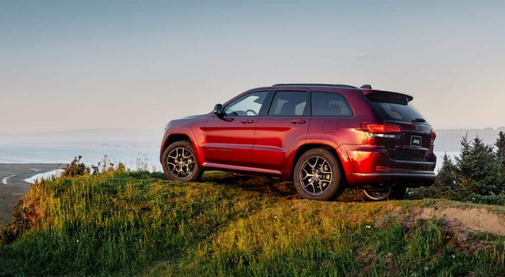 A red 2020 Jeep Grand Cherokee is parked with a beach view after leaving a Jeep dealership.