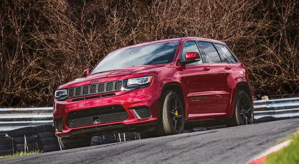 A red 2020 Jeep Grand Cherokee Trackhawk is driving around a corner on a racetrack.