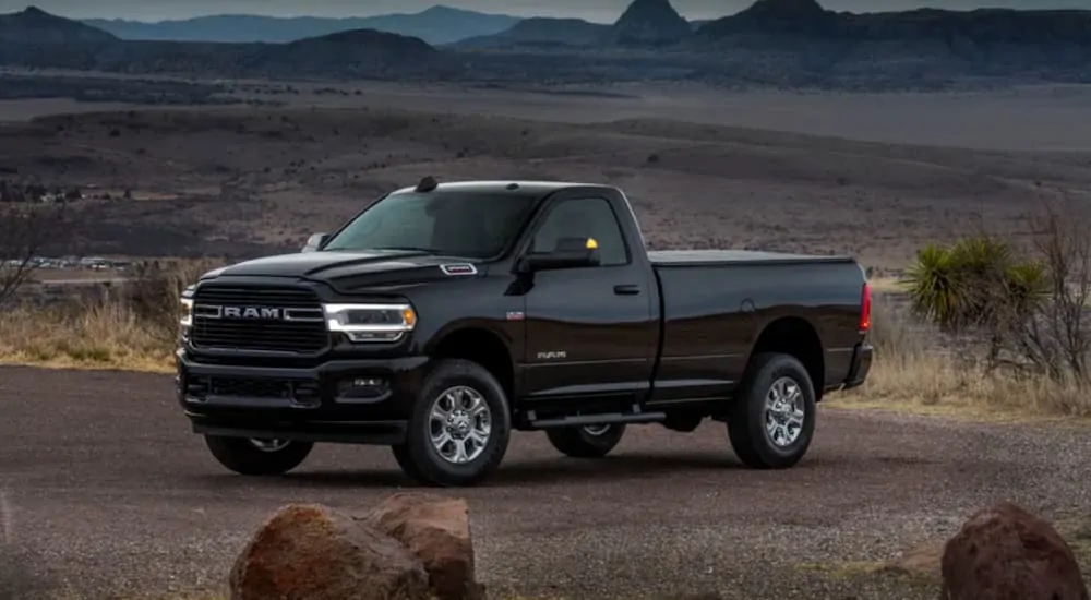 A black 2020 Ram 2500 Big Horn Sport is parked on a dirt road with distant mountains after leaving a Ram dealer near me.