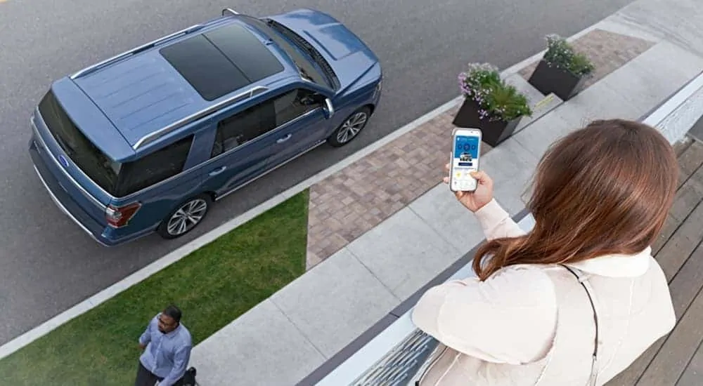 A woman is using her phone to control her 2020 Ford Expedition from her balcony.