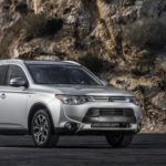 A silver 2015 Mitsubishi Outlander is parked in front of a rock face.