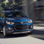 A blue 2020 Chevy Trax is driving on a city street.