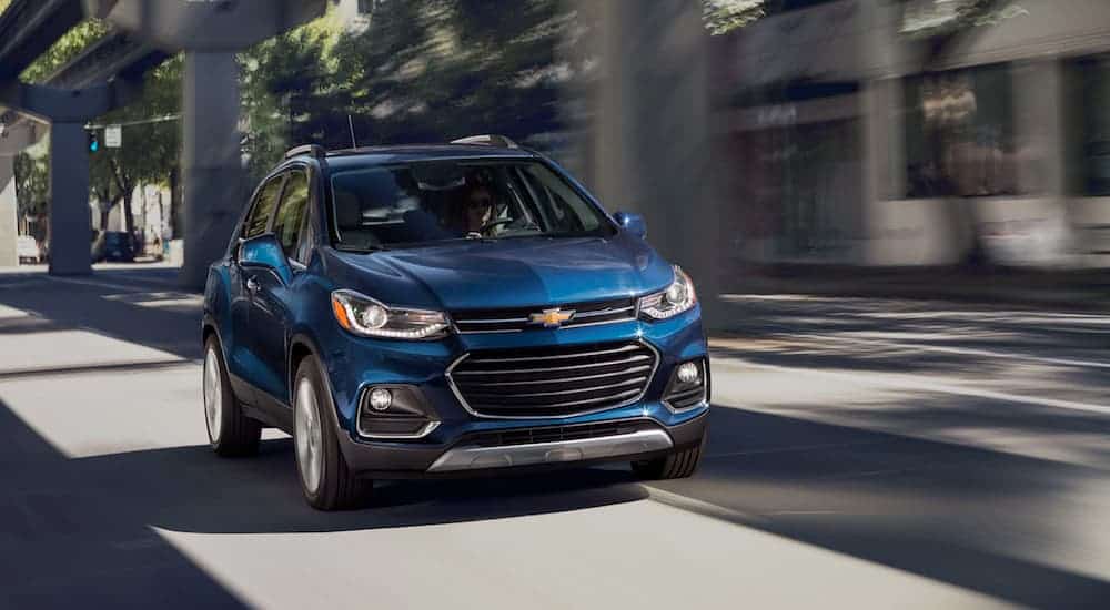 A blue 2020 Chevy Trax is driving on a city street.