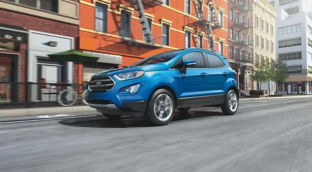 A blue 2020 Ford EcoSport is driving on a city street.