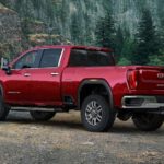 A red 2020 GMC Sierra 2500 is parked in front of rock hills and trees after winning the 2020 GMC Sierra 2500 vs 2020 Ford F-250 comparison.