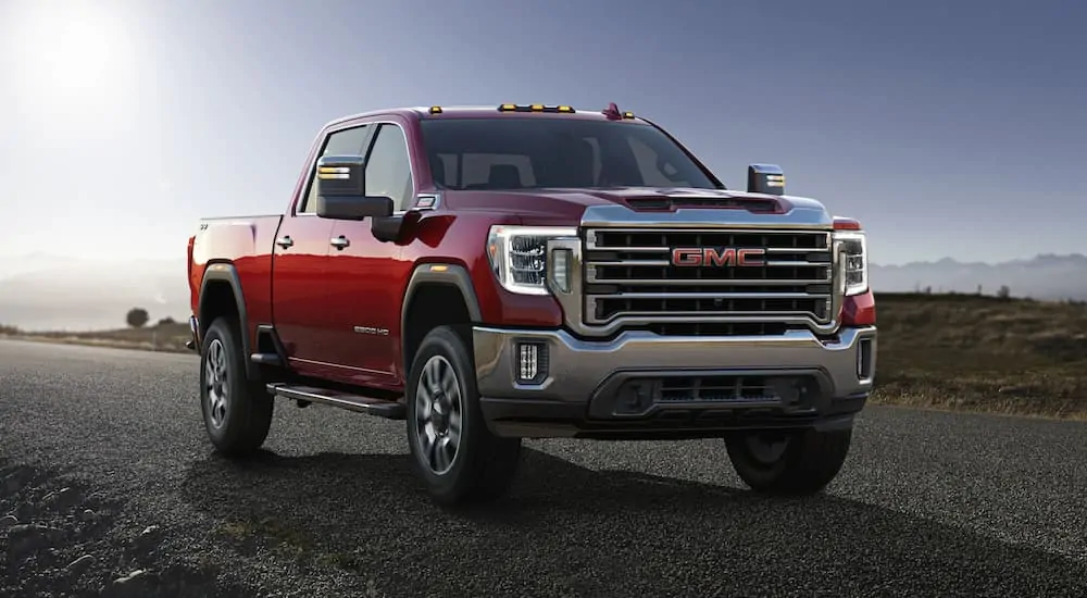 A red 2020 GMC Sierra 2500 is parked on a road with distant, hazy mountains.
