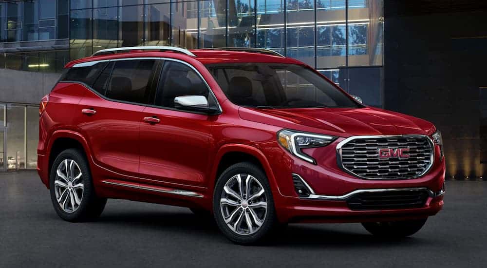 A red 2020 GMC Terrain is parked in front of a glass building after winning the 2020 GMC Terrain vs 2020 Mazda CX-5 comparison.