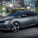 A gray 2020 Honda Civic Hatchback Sport Touring is driving in a city at night.