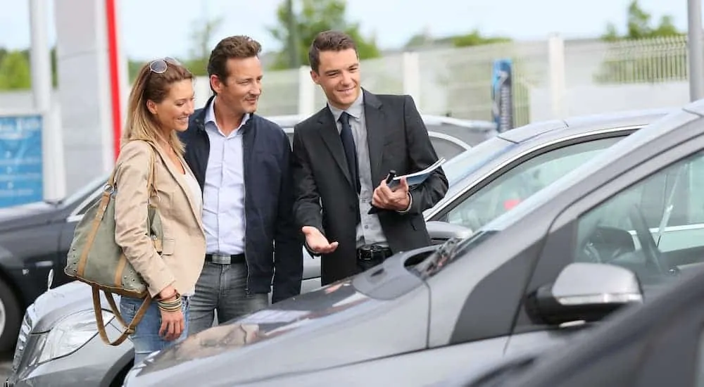 A salesman is showing a couple a car at a Cincinnati car dealer.