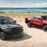 A black 2020 Ram 1500 and a red 1500 Rebel are parked on a beach.