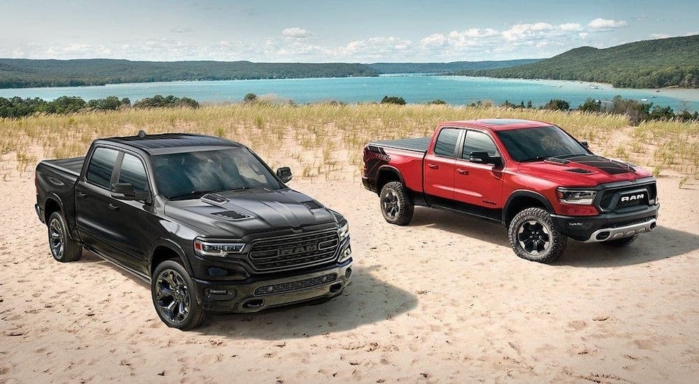 A black 2020 Ram 1500 and a red 1500 Rebel are parked on a beach.