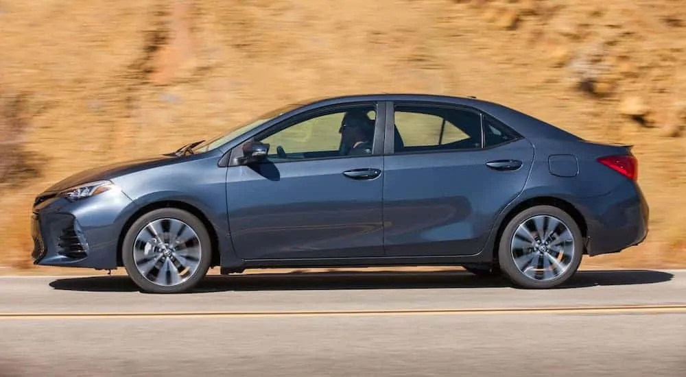 A blue 2018 Toyota Corolla XSE is driving in front of a rock face.