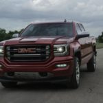 A red 2017 GMC Sierra 1500 is driving on a track.