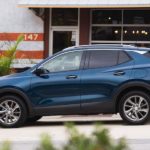 A blue 2020 Encore GX is shown from the side in front of a white building after winning the 2020 Buick Encore GX vs 2020 Mazda CX-3 comparison.