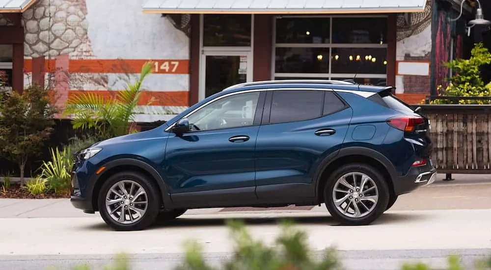 A blue 2020 Encore GX is shown from the side in front of a white building after winning the 2020 Buick Encore GX vs 2020 Mazda CX-3 comparison.