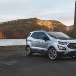 A silver 2020 Ford EcoSport is parked in front of a desert oasis.