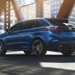 A blue 2020 Ford Edge is driving on a city bridge after winning the 2020 Ford Edge vs 2020 Chevy Blazer comparison.