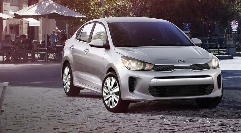 A silver 2020 Kia Rio is parked on pavers in front of a cafe.