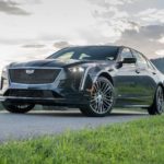 A gray 2019 Cadillac Certified Pre-owned CT6-V is parked in front of fields and hills at sunset.