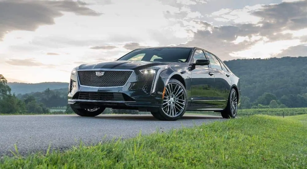 A gray 2019 Cadillac Certified Pre-owned CT6-V is parked in front of fields and hills at sunset.