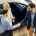 A couple is shaking the hand of a salesman after doing an end of lease turn-in.